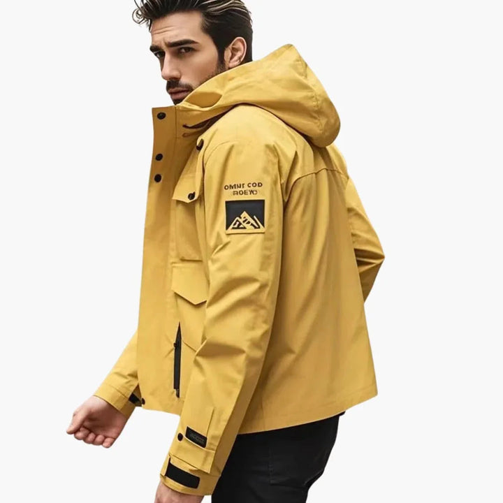 Man wearing the yellow ski jacket with the hood up, side view
