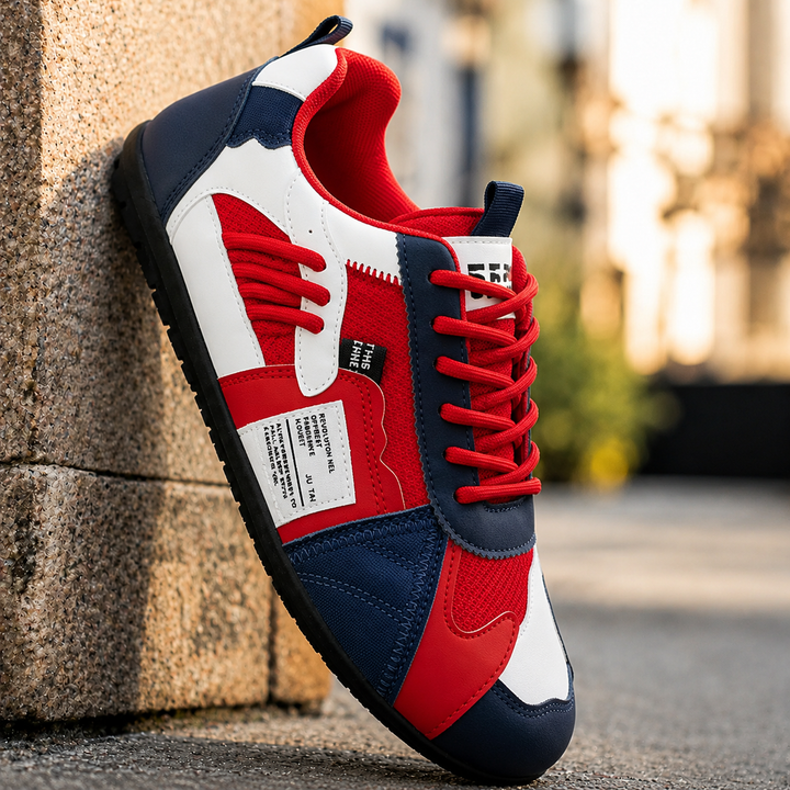 Red and navy retro lace-up sneaker, angled view against a sandstone wall