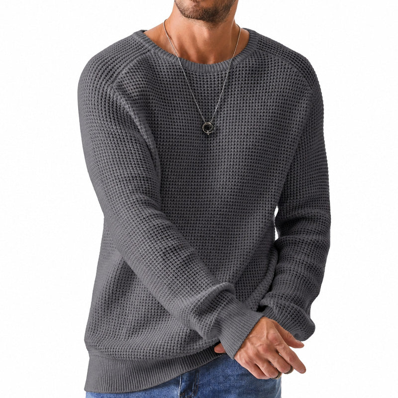 Man wearing a dark gray waffle knit crewneck raglan sweater