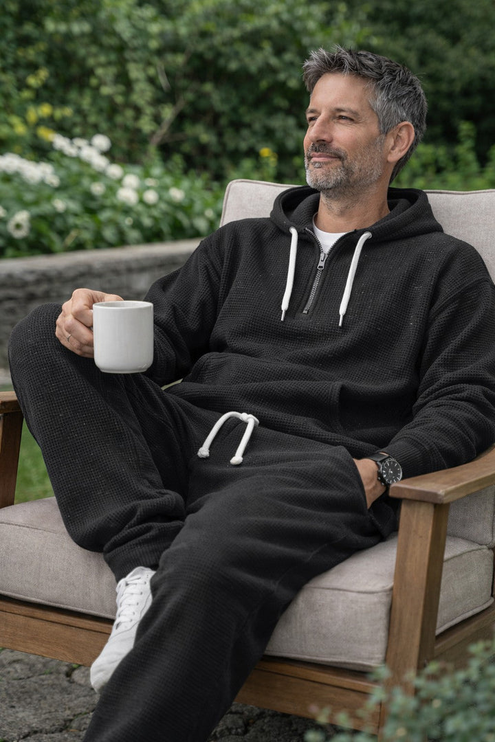Black hoodie and jogger set worn seated in a garden chair