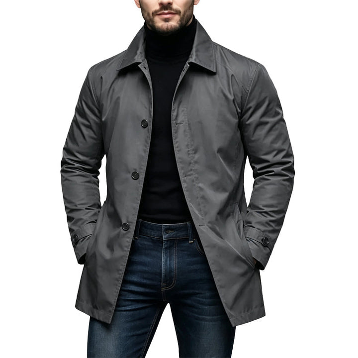 Gray single breasted trench coat worn open over a black turtleneck and jeans
