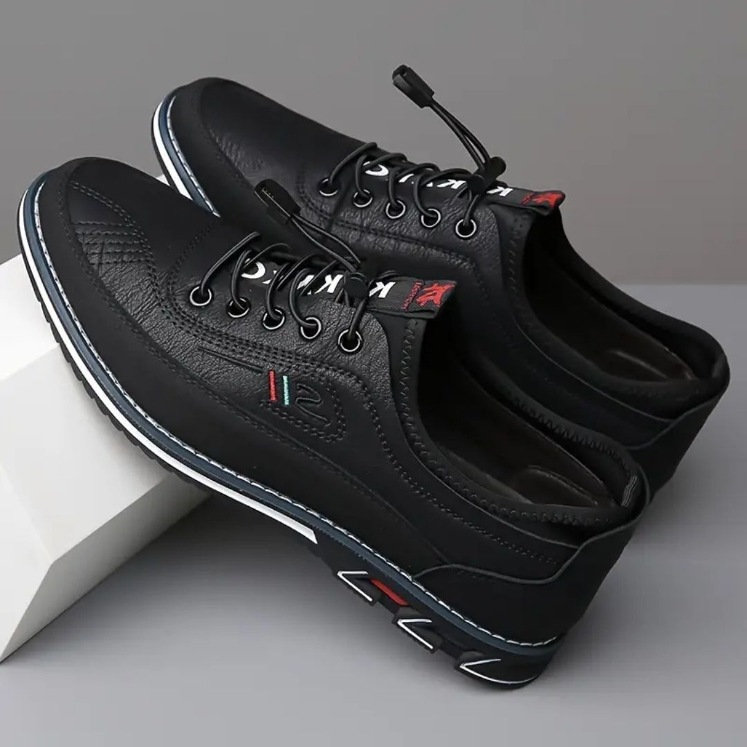 Pair of black elastic lace sneakers angled on a white block