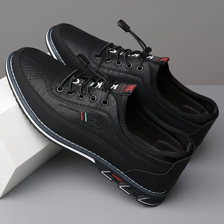 Pair of black elastic lace sneakers angled on a white block