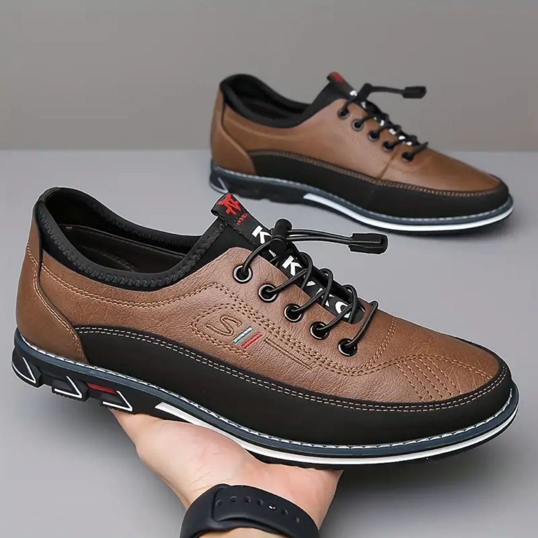 Pair of brown elastic lace two tone sneakers held in hand