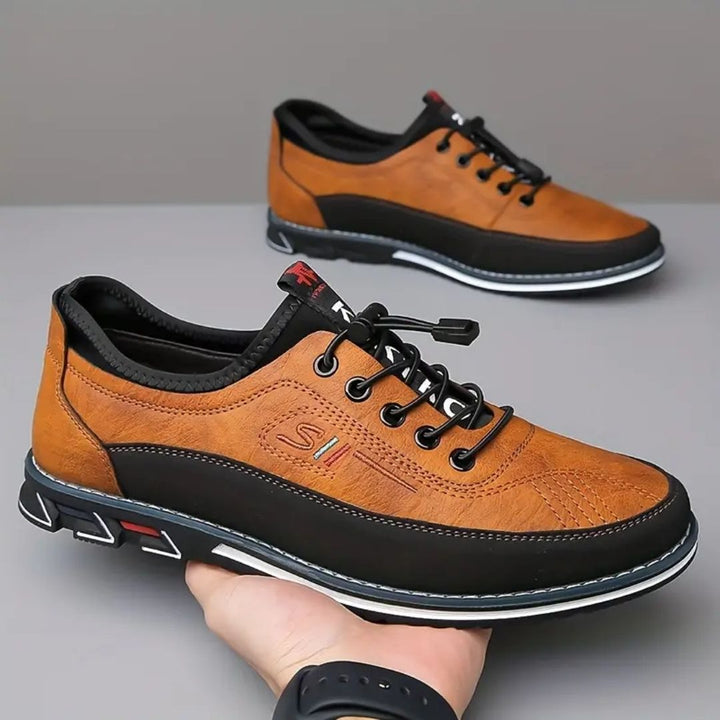 Pair of camel elastic lace two tone sneakers held in hand