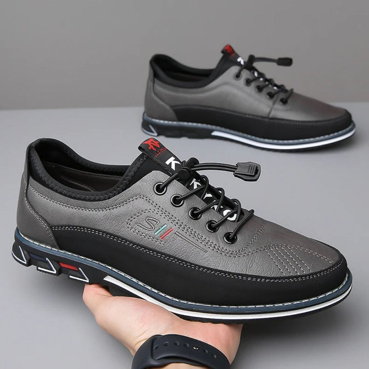 Pair of gray elastic lace two tone sneakers held in hand