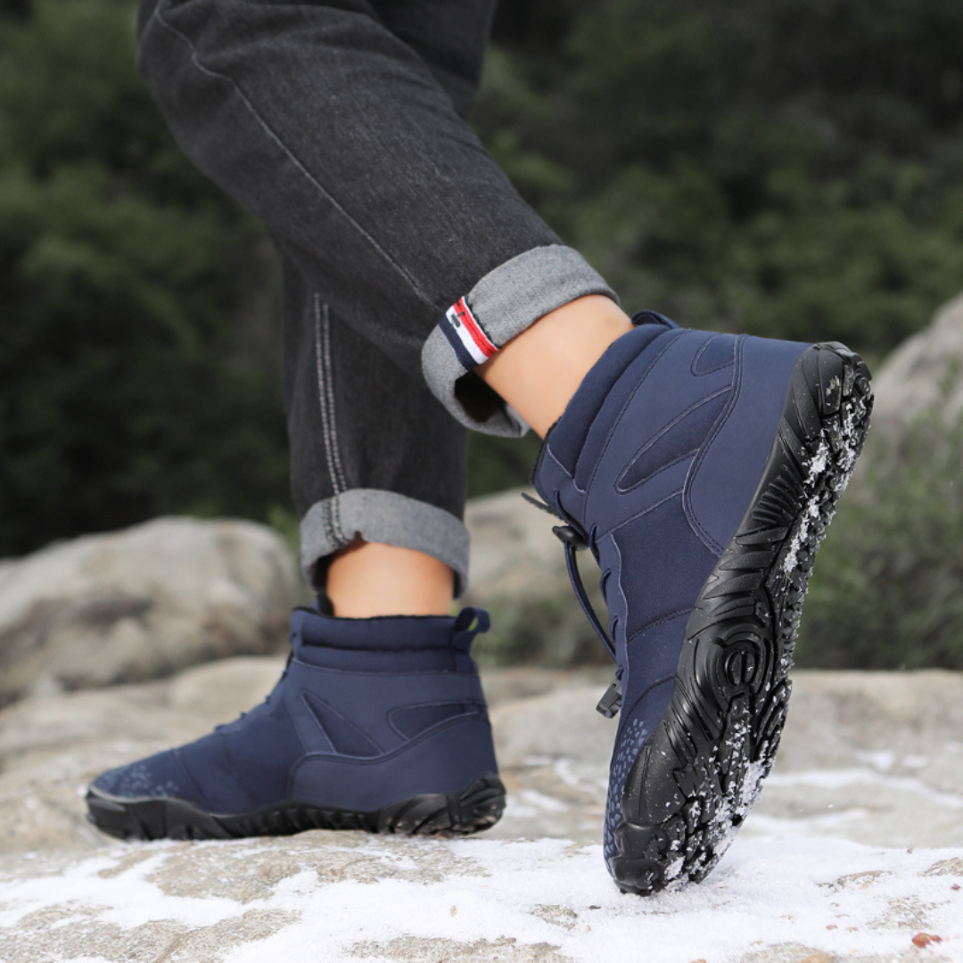 Navy ankle boots worn outdoors with cuffed jeans, one foot lifted mid step