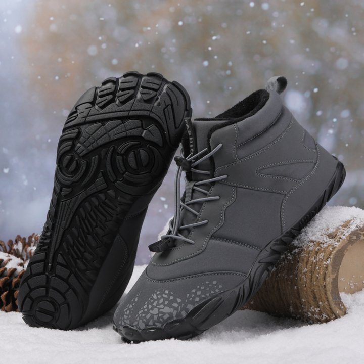 Gray ankle boot beside a black boot showing its tread sole, on snow