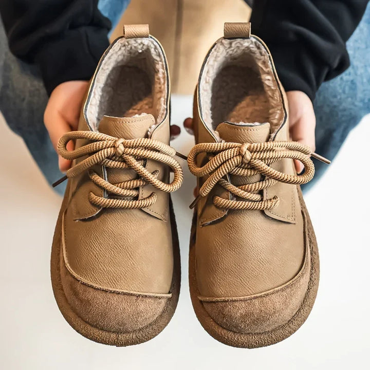 Pair of tan lace up shoes held in hands, showing the fleece lined interior