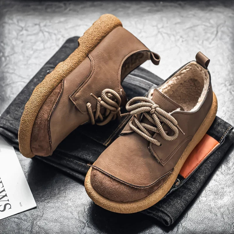 Taupe lace up shoes with crepe sole resting on folded dark jeans