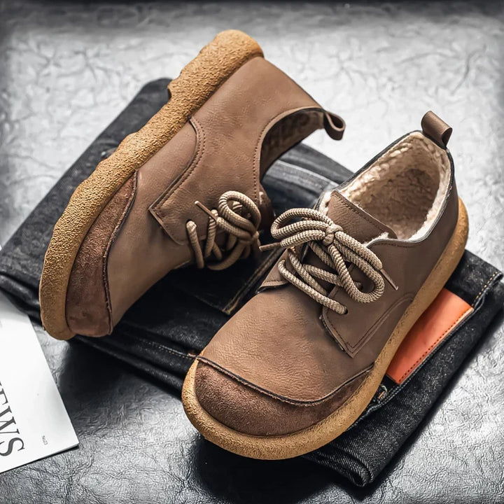 Taupe lace up shoes with crepe sole resting on folded dark jeans