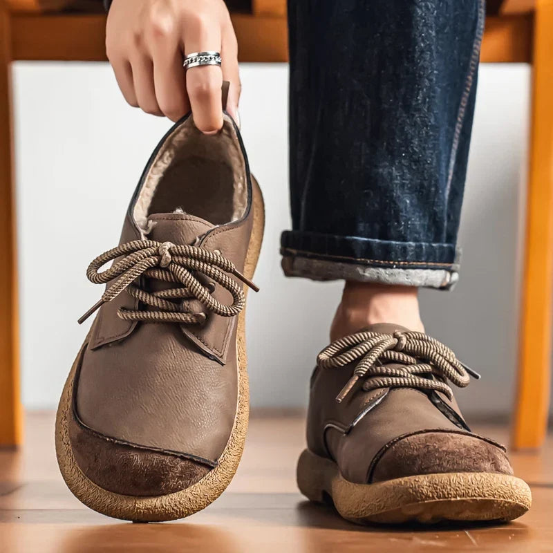 Taupe lace up shoes worn with rolled jeans on a wooden floor