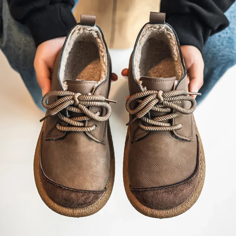 Pair of taupe lace up shoes held in hands, showing the fleece lined interior
