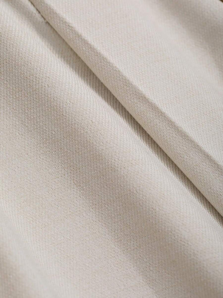 Close-up of the smooth beige fabric folds of the pleated skirt
