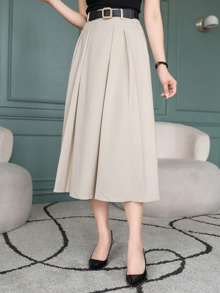 Pleated beige midi skirt with belt, model standing with one hand on hip