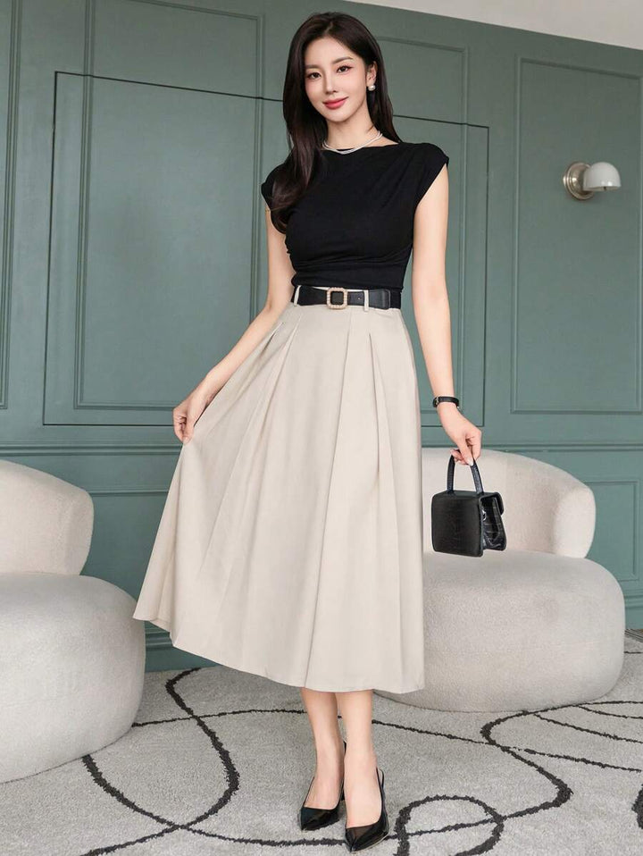 Beige A line skirt with belt loops, styled with a black sleeveless top and handbag