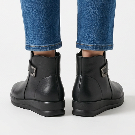 Back view of black wedge ankle boots with metal buckle at the side