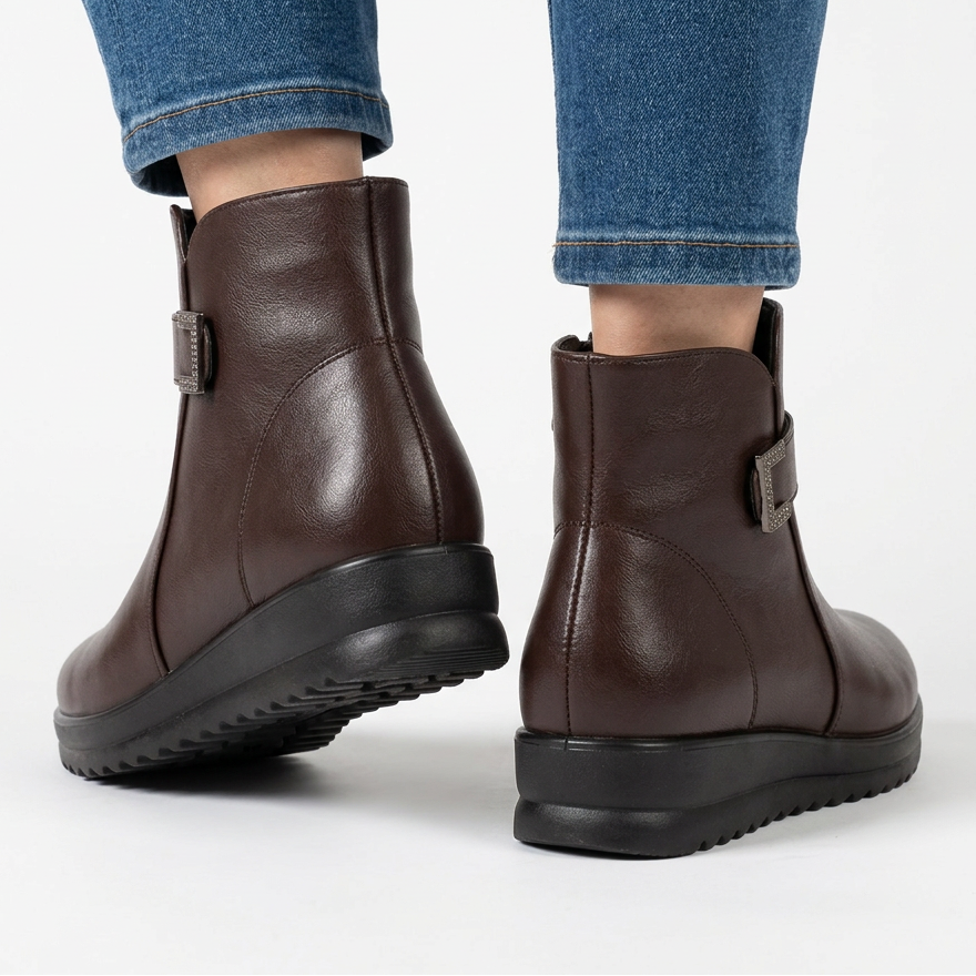 Back view of dark brown wedge ankle boots with metal buckle at the side