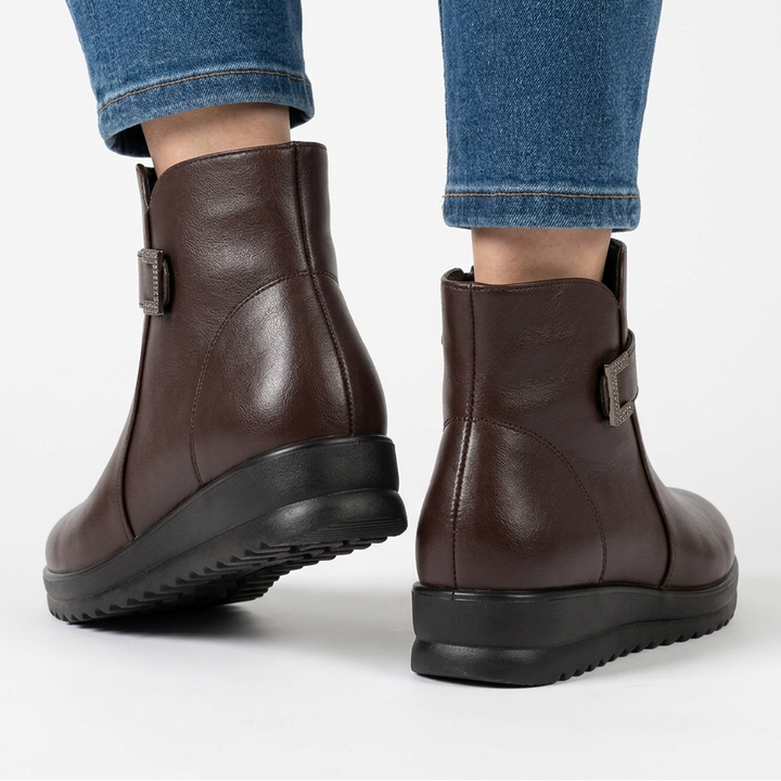 Back view of dark brown wedge ankle boots with metal buckle at the side