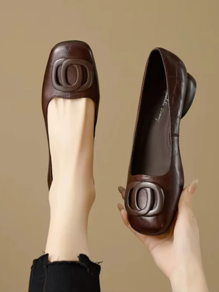 Brown square toe ballet flat with ring detail held in a hand