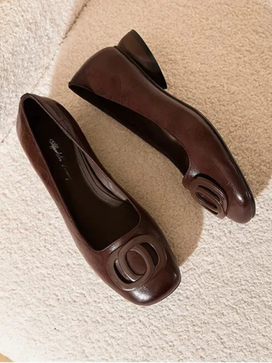Pair of brown square toe ballet flats with ring detail seen from above on a soft rug