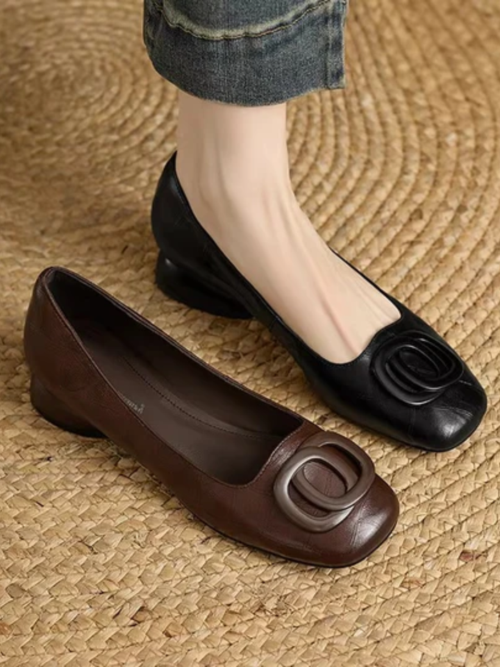 Brown and black square toe ballet flats with ring detail side by side on a woven mat