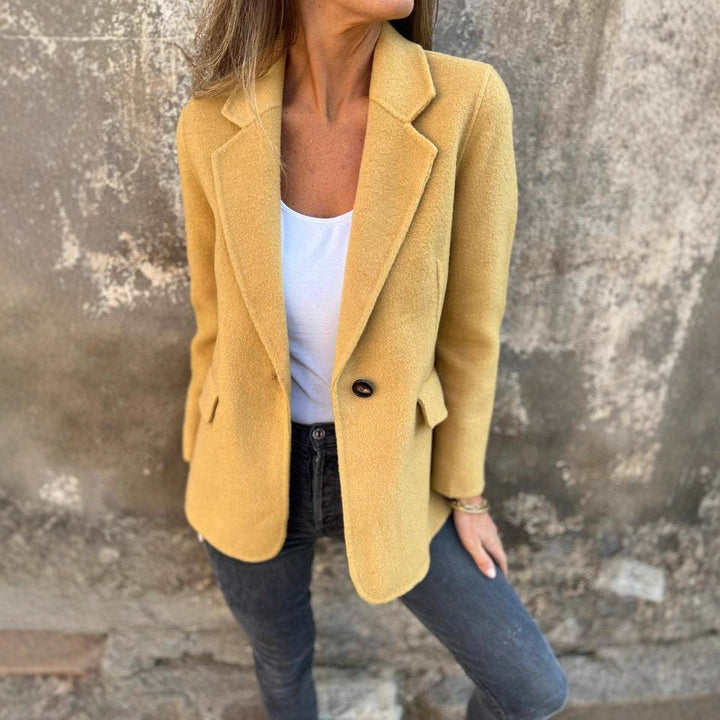 Yellow tailored blazer with notch lapels against a stone wall