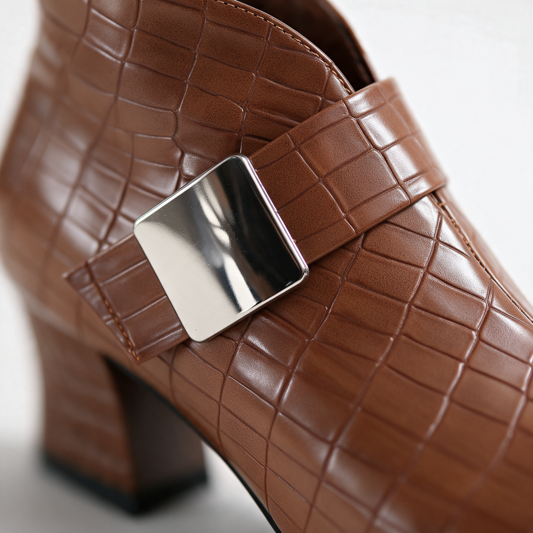 Close-up of the metal buckle strap and block heel on the cognac boot