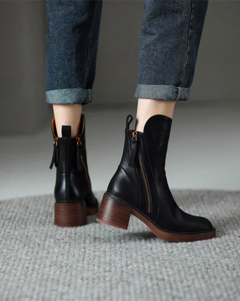 Front view of black block heel ankle boots with side zip worn with rolled jeans