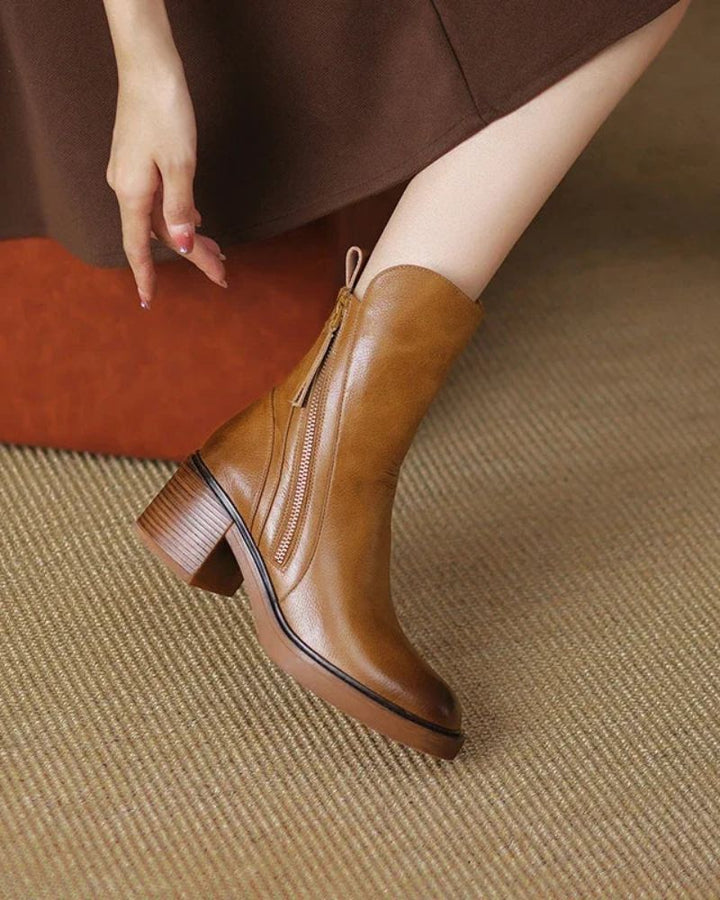 Tan block heel bootie with side zip, side view on a woven rug