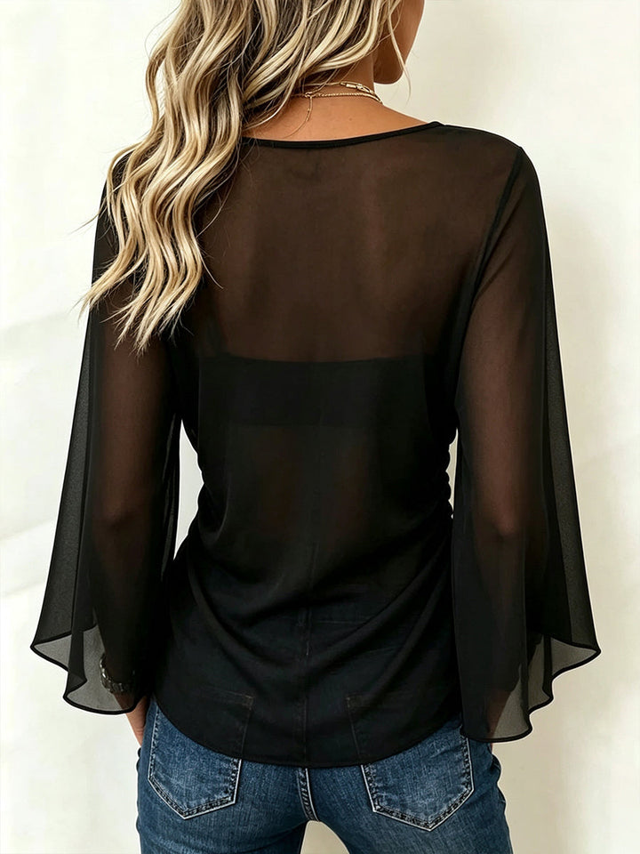 Back view of the black blouse with sheer shoulders and flared sleeves