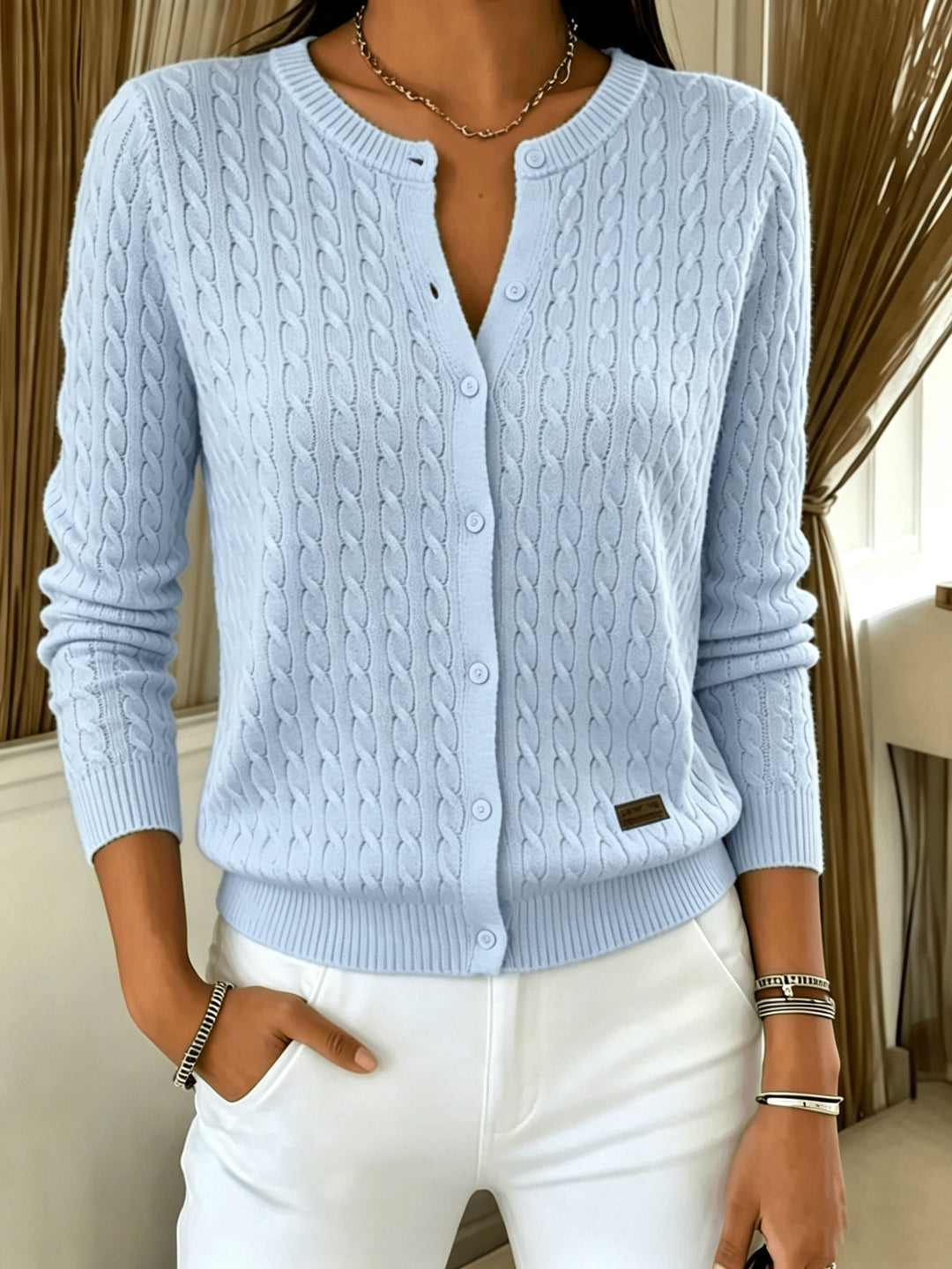 Light blue cable knit cardigan with button front, hand in pocket