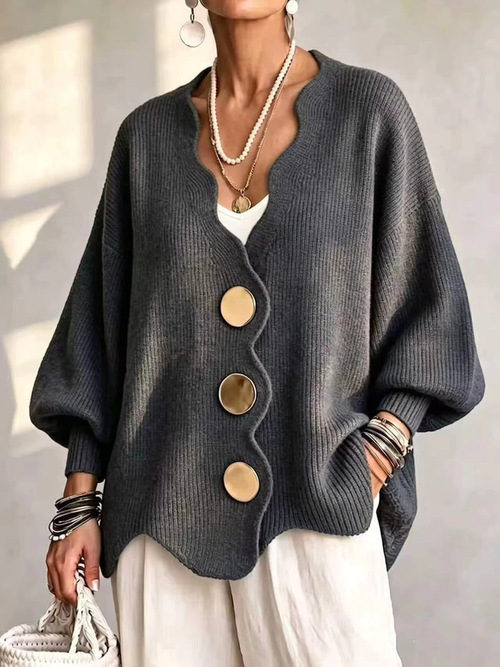 Dark gray oversized v neck cardigan with gold buttons and scalloped hem on a model