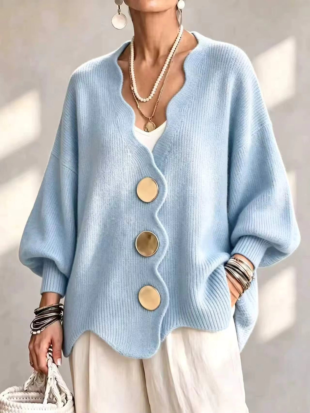 Light blue oversized v neck cardigan with gold buttons and scalloped hem on a model