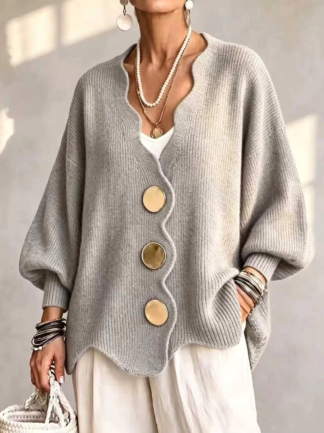 Light gray oversized v neck cardigan with gold buttons and scalloped hem on a model