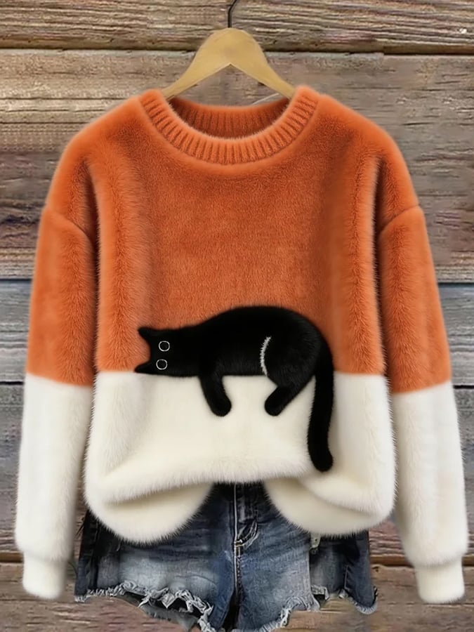 Orange oversized cat sweater with cream lower section, hanging on a wooden hanger