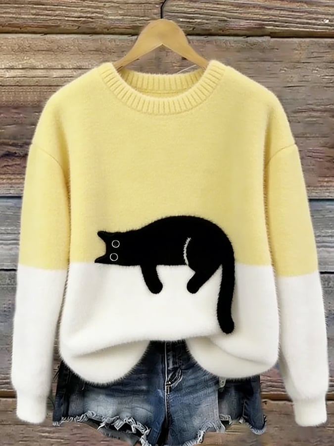 Pale yellow two tone knit sweater with a black cat resting on the white section