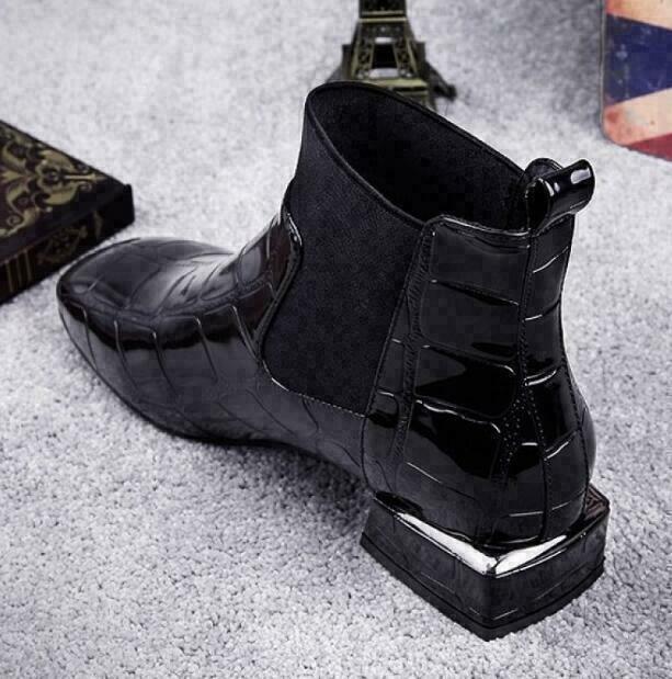 Front three-quarter angle of the black Chelsea boot showing the square toe and metallic heel