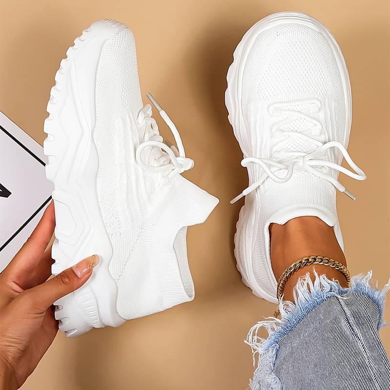 Women's white chunky sneakers, pair held in hand