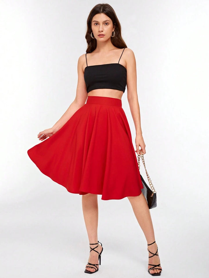 Red circle skirt styled with a black cami top and heels, full length view