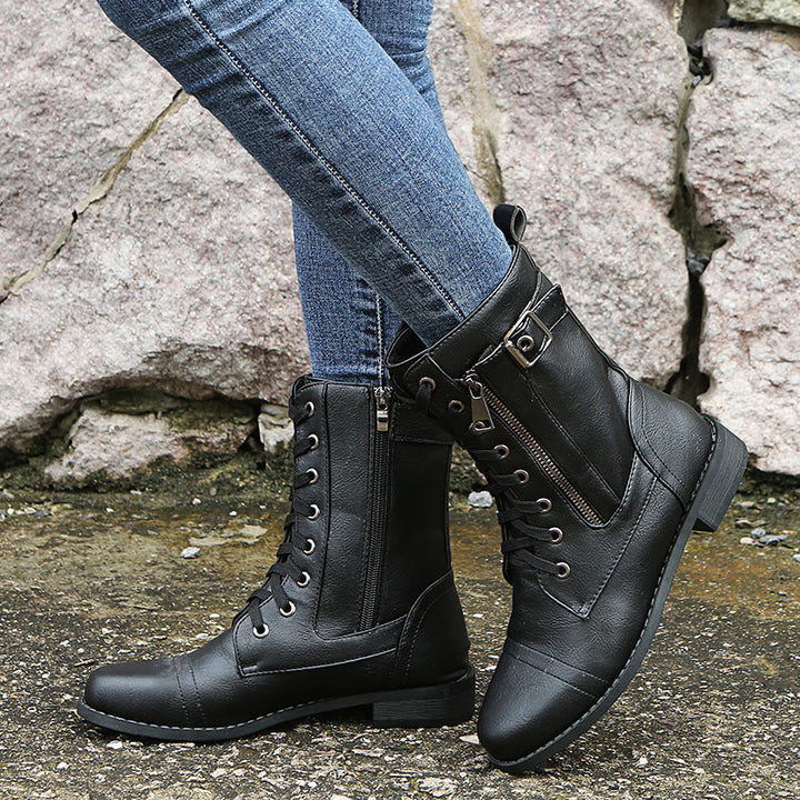 Black lace up combat ankle booties with buckle detail worn with jeans on gravel