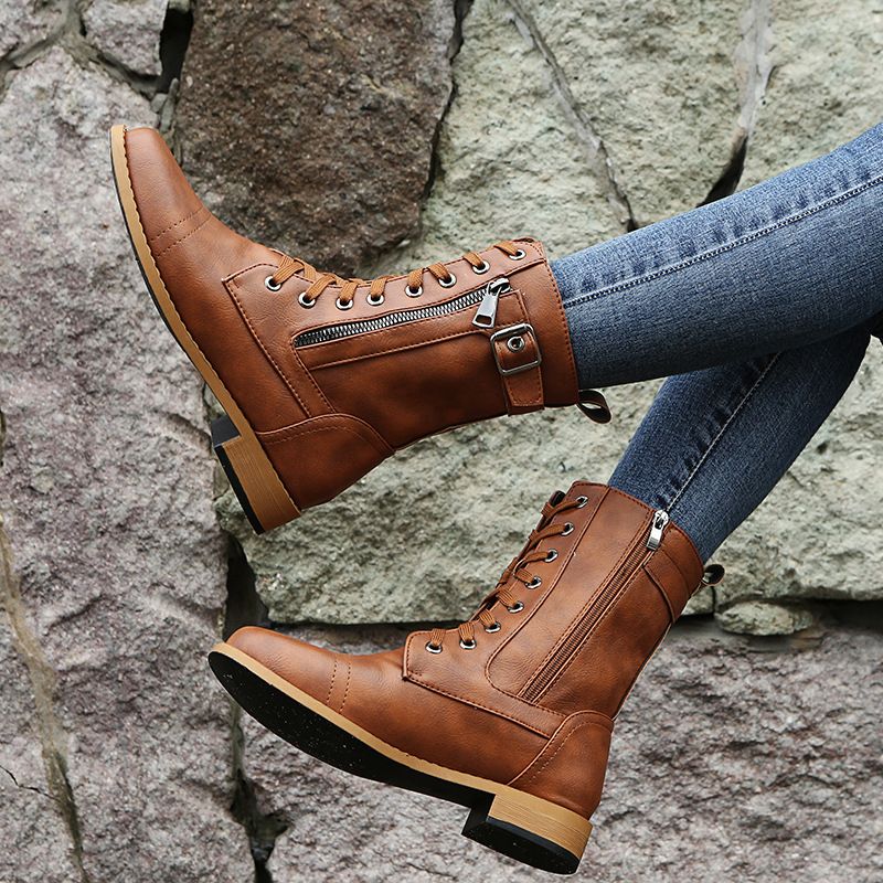 Cognac lace up combat boot raised to show the side buckle and zip