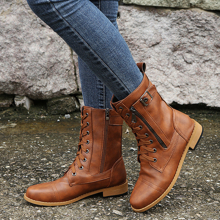 Cognac combat booties with lace up front and block heel worn with jeans on gravel