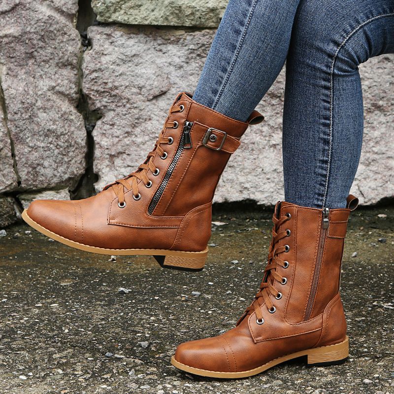Cognac lace up combat ankle boots with one foot lifted, side view