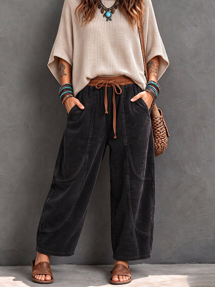 Black corduroy pants with tan drawstring, styled with a woven bag