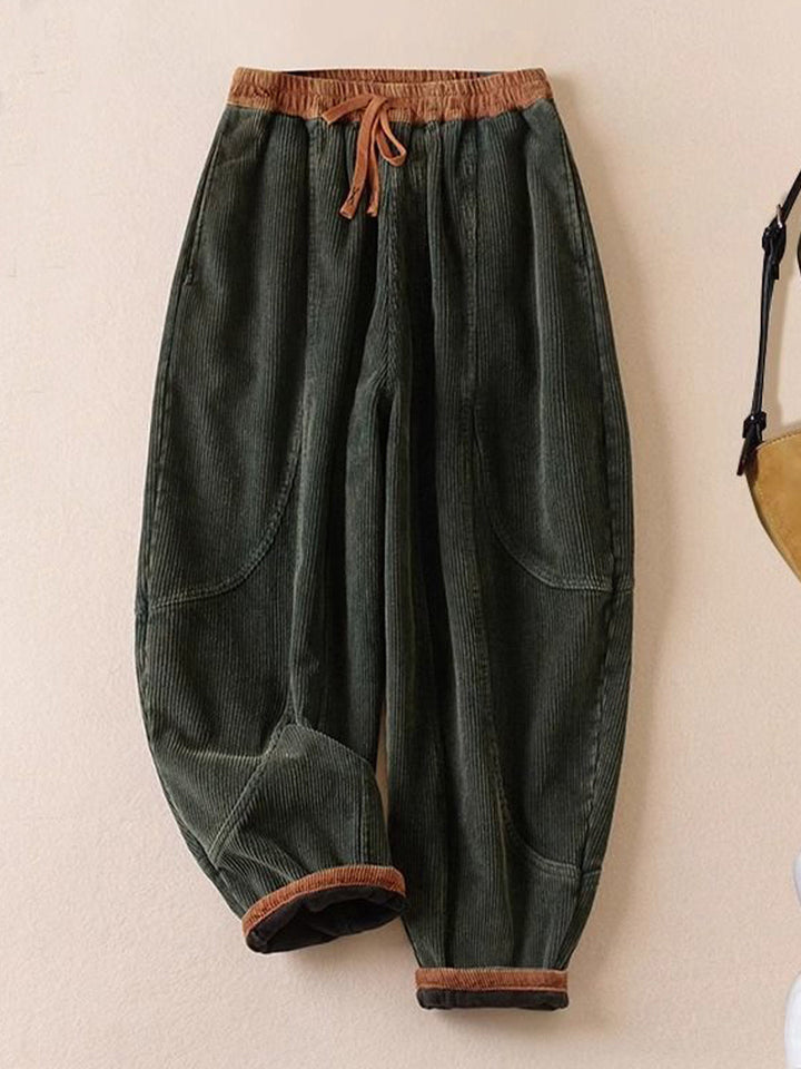 Dark green corduroy pants laid flat showing the elastic waist and banded ankles