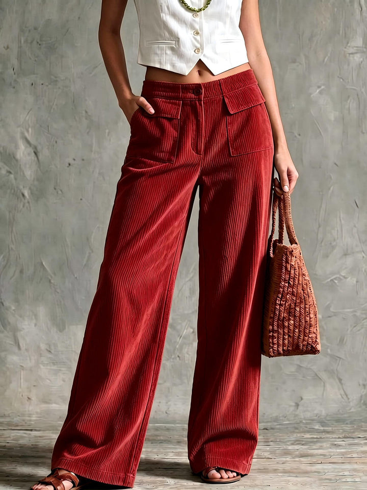 Red corduroy pants worn with a cropped white vest and woven bag