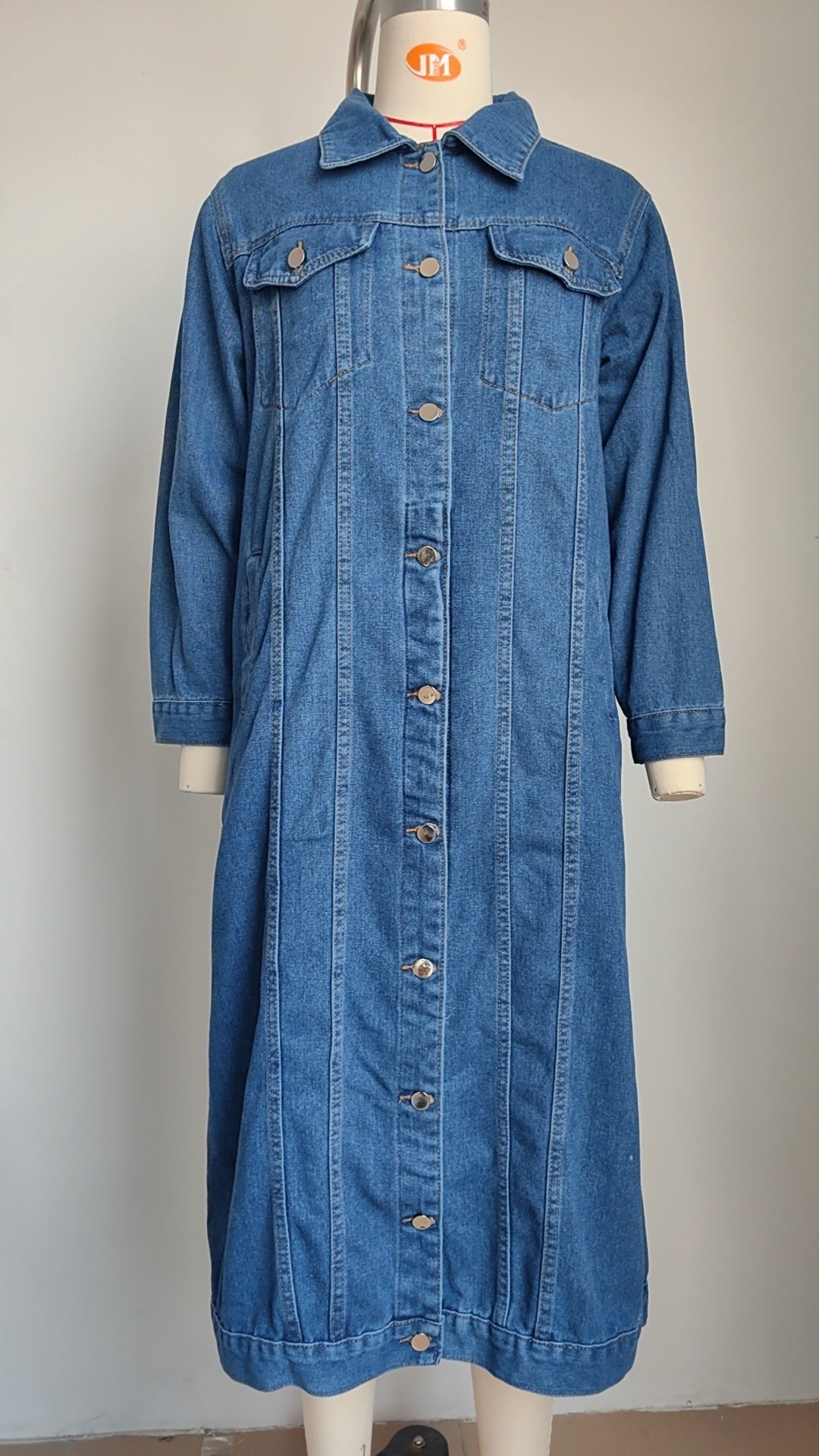 Blue denim trench coat on a dress form showing flap chest pockets and button placket