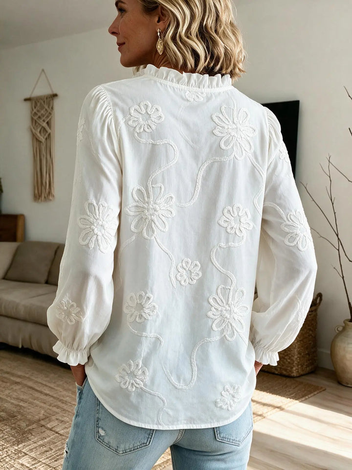 Back of the white blouse with floral embroidery and ruffled stand collar