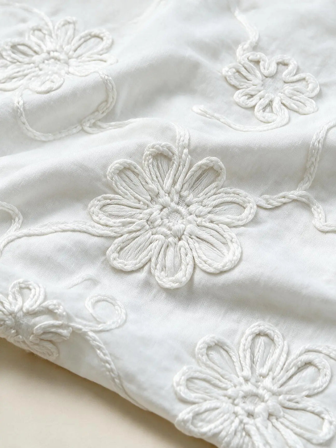 Close-up of the raised floral embroidery on the white blouse